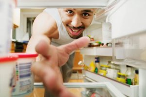 Ragazzo che prende lo yogurt in frigo